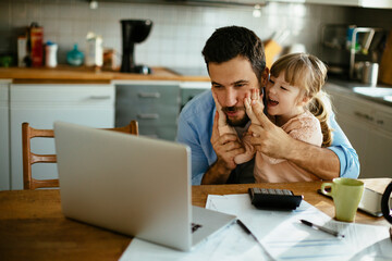 Young father and daughter using a laptop together in the morning