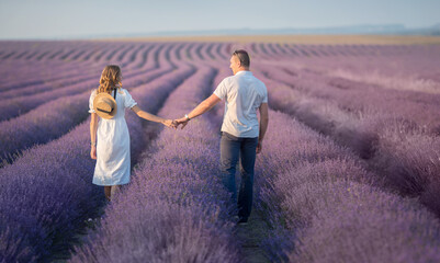  man and a woman are walking they walk hand in hand through the field with lavender