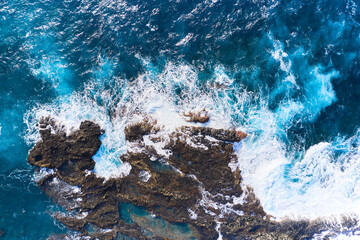 Salty sea water boils near the stones. Powerful waves crash against the rock