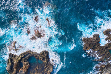 Top view of powerful waves and solid rocks. Texture and texture of sea water