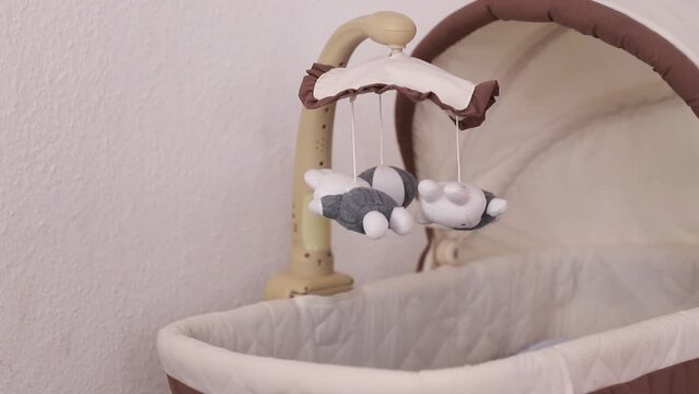 Carousel in a baby cot with spinning white-gray toys.