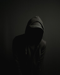 Scary faceless criminal hacker man in black hoodie and hat
