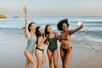 Capturing summer vacation time. Carefree diverse women taking picture together at the beach, making memories