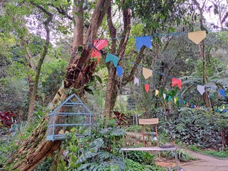 Guarulhos, S&atilde;o Paulo, Brazil - June 30, 2022. View of garden decorated with pennants, table, chair and birdcage in Bosque Maia.