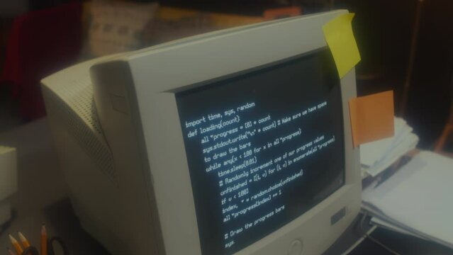 No people medium close-up shot of old computer monitor with code on screen on table in 90s garage office