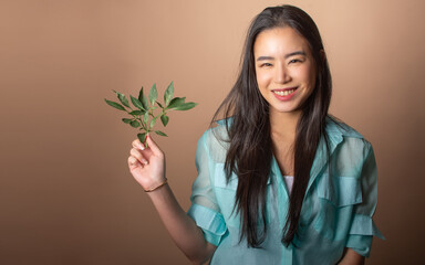 Asian beautiful woman holding green leaf, presenting sustainable environment, smiling with happiness on isolated background, copy space. Environmental saving Concept.