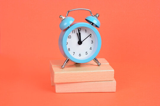 Empty wooden blocks with alarm clock on a orange background