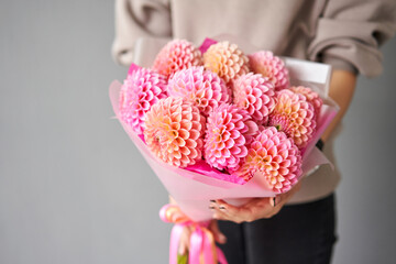 Mono bouquet of pink dahlias. Beautiful bouquet of flowers in womans hands. the work of the florist at a flower shop. Handsome fresh bouquet. Flowers delivery - 624145563