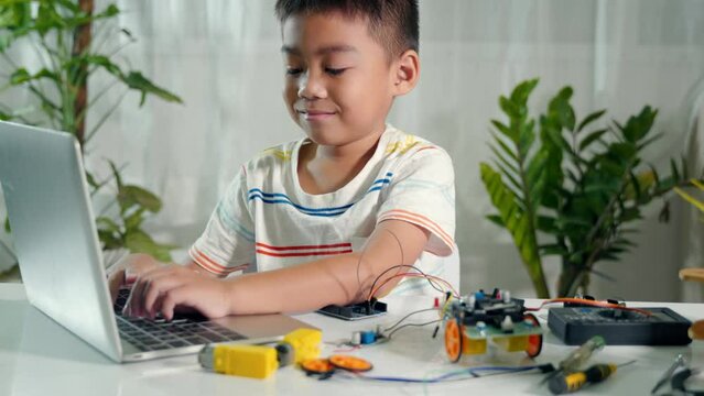 Asian kid boy learns coding and programming with laptop for Arduino robot car, Little child students typing code in computer with car toy, STEAM education AI technology course school learning