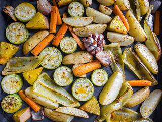 background with baked vegetables in the oven: potatoes, carrots, peppers, garlic, onions, zucchini