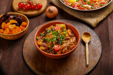 hot cholent sprinkled with green onions on a laid Shabbat table.