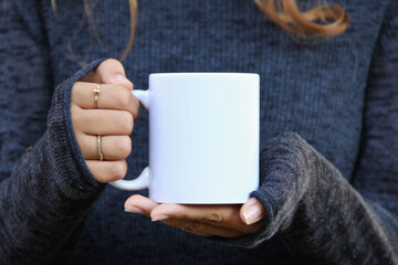 Girl is holding white mug in hands. Blank 11 oz white cup