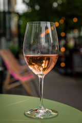 Glass of refreshing rose wine on a table of a city cafe terrace on summer evening. Street in bokeh.