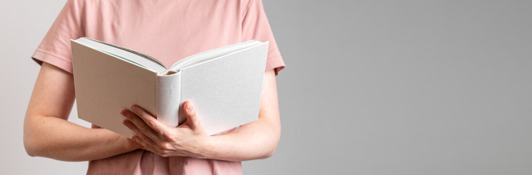Hand holding white open book, reader student. Banner background