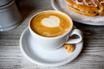 cup of cappuccino with a small cookie on the side