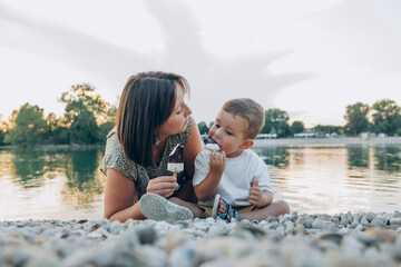 Woman with her son enjoying family time walking on the lake together , eating ice cream. Happy...