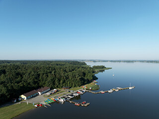 Jezioro i łodzie na wodzie obok las i niebieskie bezchmurne niebo.  © klumb
