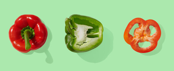 Green, red and yellow peppers on green pastel background