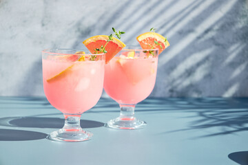 Cold drinks with citrus fruits on a bright sunny day in the shade of palm trees. Summer refreshing cocktails with fresh fruits.