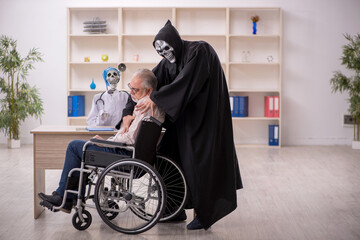 Old patient in wheel-chair visiting two devil doctors