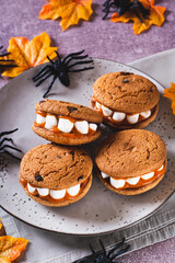 Halloween treats cookies with marshmallow teeth on a plate and spiders vertical view