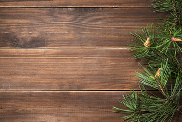 Flat lay of pine branches. Coniferous tree decoration on a brown wooden background. Festive new year concept or product mockup.