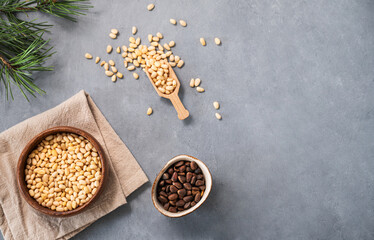 Pine nuts in a bowl  on napkin and scattered on a blue background with branches of pine needles....