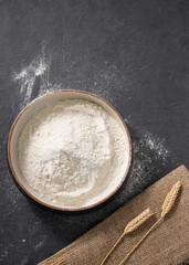 Wheat flour is scattered on a dark background with napkin. Organic baking ingredients. Concept of homemade and healthy food.