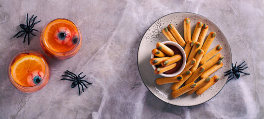 Halloween savory breadsticks with pumpkin seed nails on ketchup on a plate top view web banner