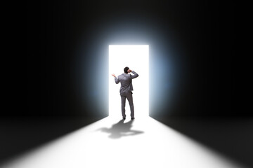 Businessman entering backlit door in escape concept