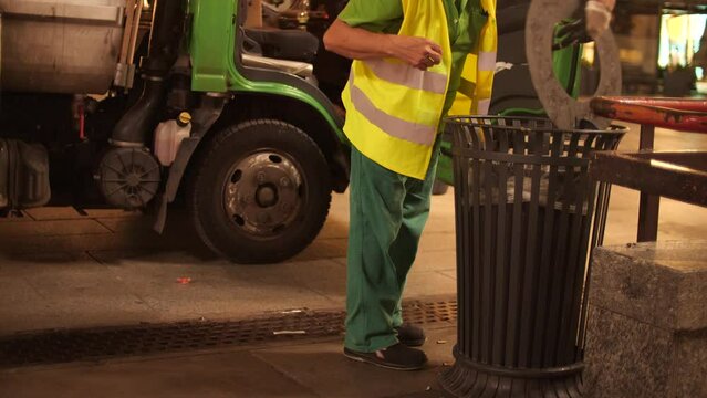 Unknown street janitor or garbage man at work the centre of Milan in the evening, Italy
