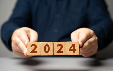 Man holding blocks with 2024. The beginning of a new year. Embracing new trends, making forecasts, setting plans for the upcoming year. Reflecting on past achievements and experiences, looking forward