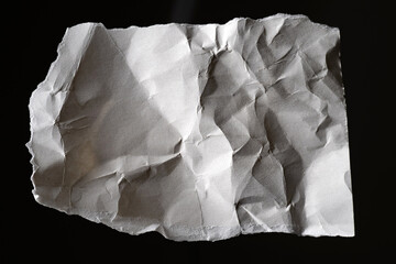Piece of old paper. Torn white sheet. Wrinkled white material. Paper isolated on black background....