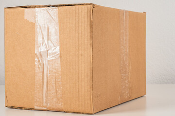 Cardboard box. Package wrapped with tape. Cardboard box for mailing. Parcel on gray background. Box without labels. Large cardboard parcel close-up. Cardbox for storage and transport