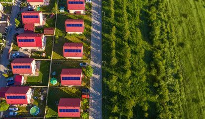 Cottage village. Country houses top view. Cottages with solar panels on roofs. Green meadow and...