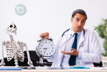 Young male doctor and skeleton patient in time management concep