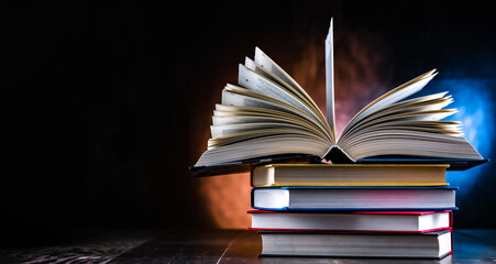 A composition with an open book lying on a stack of other books