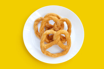 Soft pretzels on white plate on yellow background.