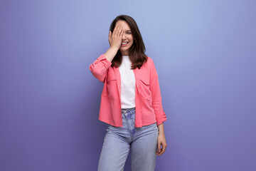 young woman in a pink shirt and jeans with a smile on a studio isolated background