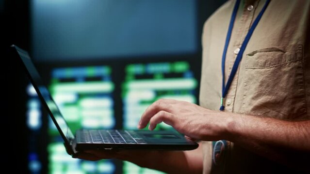 IT developer using laptop to monitor server farm security to protect information access, making sure virus protection software is updated and hackers trying to penetrate systems are rejected, close up