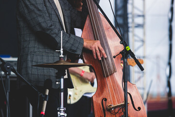 Concert view of a contrabass violoncello player with vocalist and musical rock band during jazz...