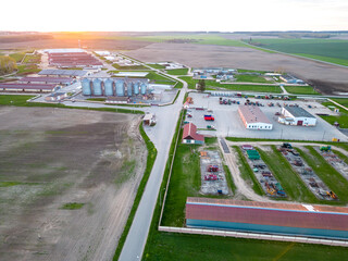 Flying a drone over silver silos on agro manufacturing plant for processing drying cleaning and storage of agricultural products, flour, cereals and grain. Large iron barrels of grain. aerial view