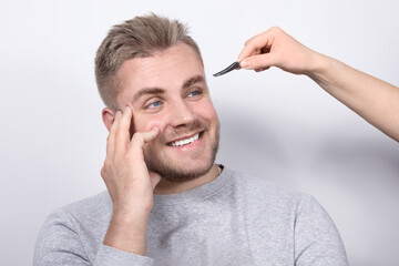 A real young blond with blue eyes and a snow-white open smile undergoes an eyebrow correction...