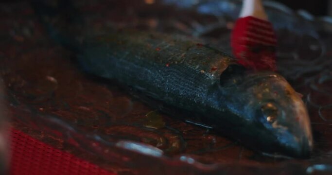 sauce is spread on the fish, the sea bass fish is prepared for the oven