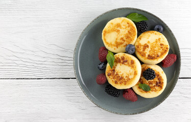 Syrniki or cottage cheese pancakes with berries on white background. Top view. Copy space. Russian, ukrainian food