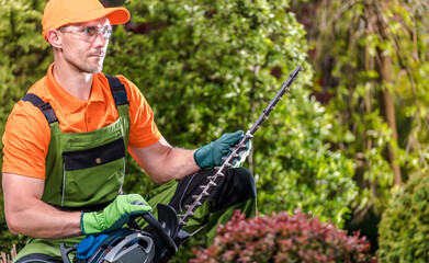Professional Gardener with His Powerful Shrub Trimmer