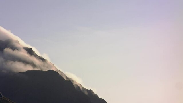 Panning shot of fog rising from mountain peak in Haukland beach, Lofoten