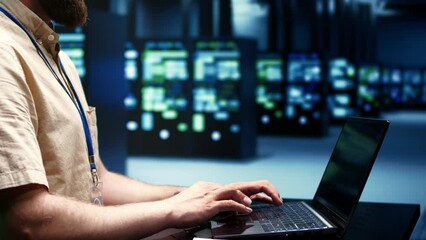 Supervisor running blade servers diagnostic tests and bug checking utilities to determine and repair software issues. Technician using laptop to survey critical systems, checking for flaws, close up