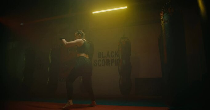 female fighter training alone in fight club, practicing punches by hands and legs, 4K, Prores