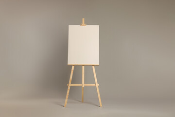 Wooden easel with blank canvas on grey background